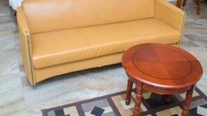 A hotel room with a bed, a sofa, and a small wooden table. - Classicus Inn Hotel (Ibadan)