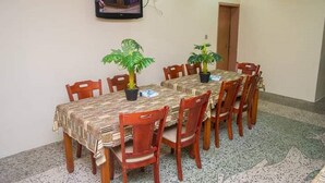 A conference room with a long table, chairs, potted plants, and a mounted TV on the wall. - Classicus Inn Hotel (Ibadan)