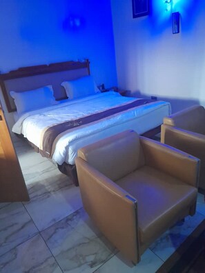 Un dormitorio con una cama, dos sillones de cuero y una mesita de noche.
