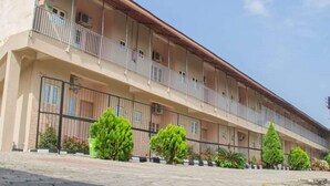 A multi-story building with balconies, a paved courtyard, and greenery. - Classicus Inn Hotel (Ibadan)