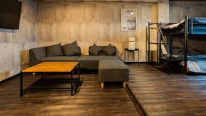 Una sala moderna con un sofá seccional, una mesa de centro de madera y una cama nido.