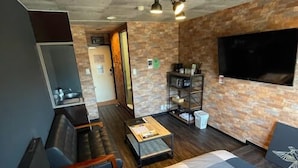 Una habitación de hotel moderna con una cama grande, un sofá, una mesa de centro, un televisor y una chimenea.