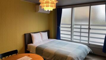 Una habitación de hotel con una cama, una mesa con una silla, una ventana con cortinas y una lámpara en el techo.