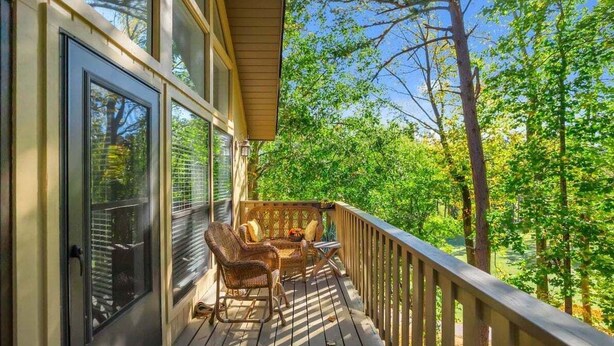 A wooden deck with wicker furniture and a view of a forest. - Marina Village 338 In Keowee Key (Salem)