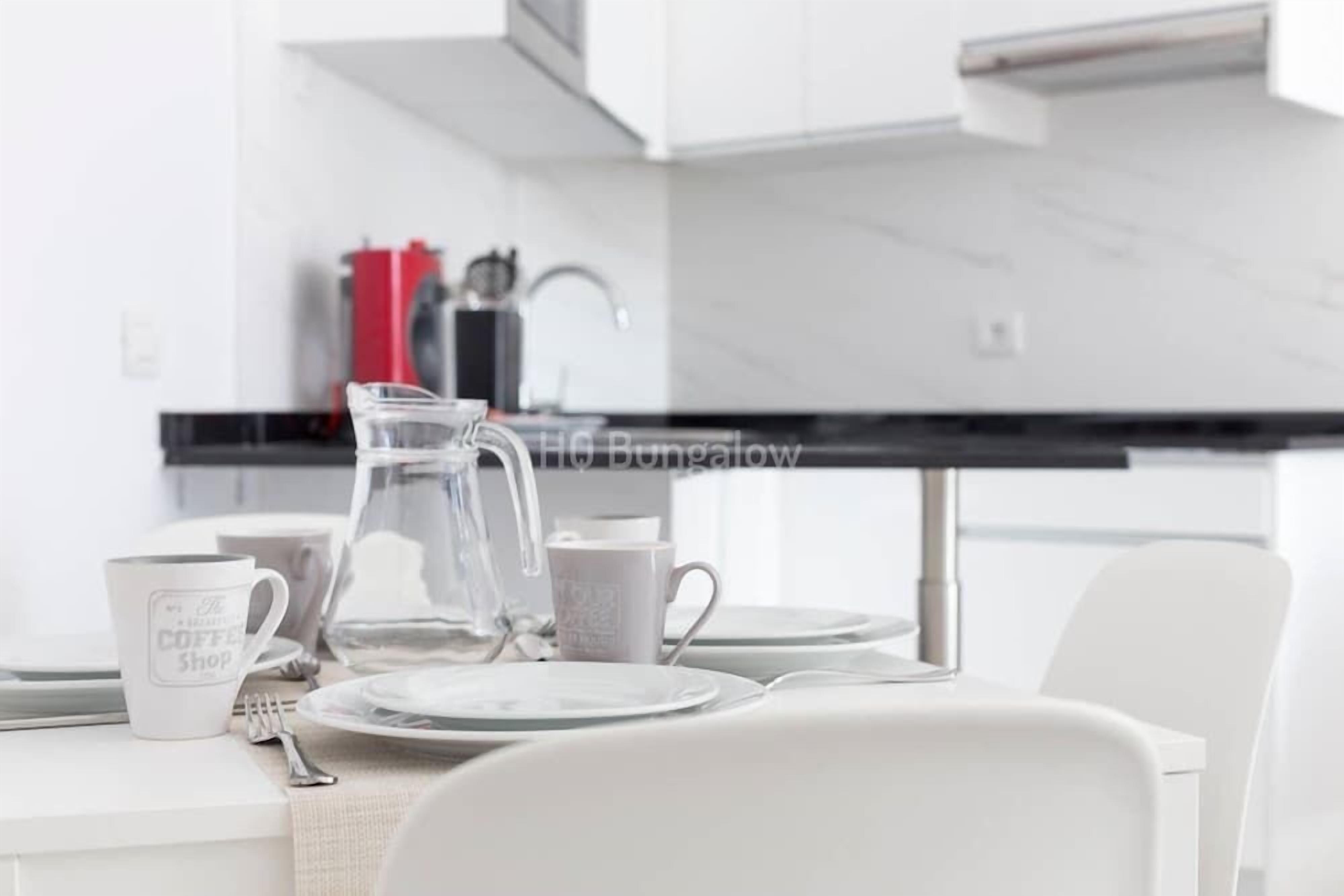 Una cocina moderna con armarios blancos, una encimera de mármol y una cafetera.