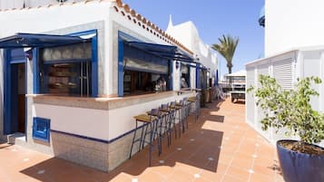 Un restaurante con terraza, un patio empedrado y una planta en maceta.