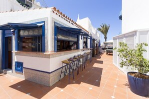 A restaurant with outdoor seating, a tiled patio, and a potted plant. - Playa Flor Chill Out Bungalows (Arona)