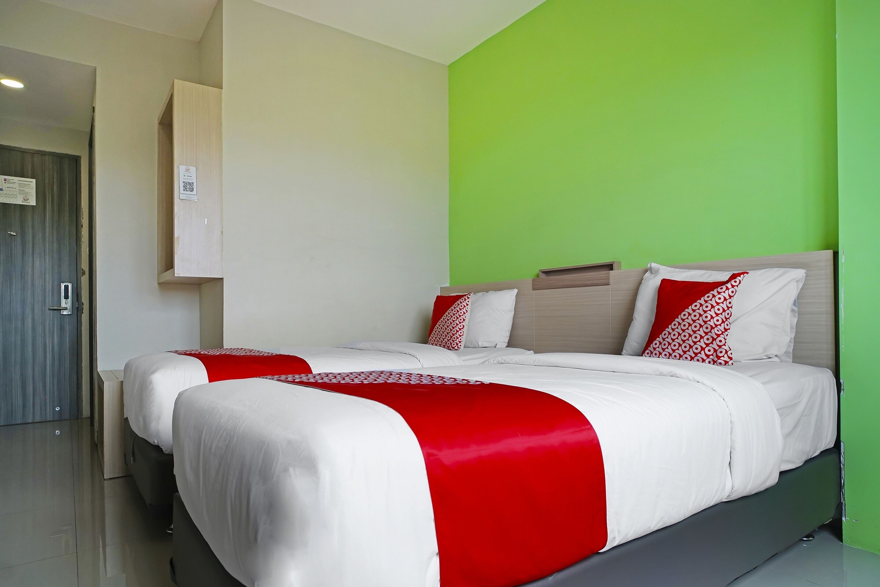 Une chambre d’hôtel avec un grand lit, un mur d’accent de couleur verte et une porte avec une pancarte.