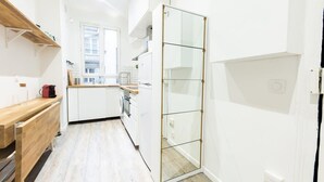 Una cocina moderna con armarios blancos, encimera de madera y una puerta corredera de vidrio.