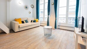 Una sala de estar moderna con un sofá, una mesa redonda de centro y un televisor sobre un mueble bajo.