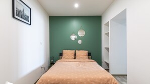 A bedroom with a bed, a green wall, and a framed picture. - Le Besson Bey - Appartement de Standing T2 (Angoulême)