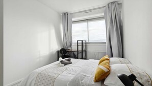 Une chambre d’hôtel avec un lit, un bureau et une fenêtre avec des rideaux.