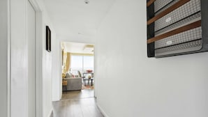 Un couloir au plancher de bois mène à un espace de vie comprenant un canapé et une table à manger.