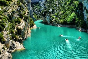 A turquoise river surrounded by rocky cliffs and dense greenery.