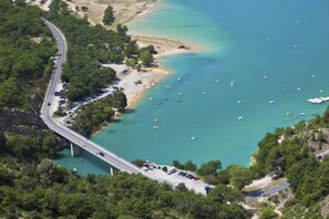 Une vue aérienne d’une route côtière avec un pont, une plage et des bateaux sur l’eau.