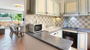 A modern kitchen with a microwave, stove, and dishwasher. There is a dining area with chairs and a table. - Apartment in Gréoux-Les-Bains near Lakes (Gréoux-les-Bains)