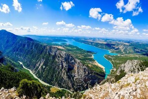 Eine gebirgige Landschaft mit einem gewundenen Fluss und blauem Himmel.