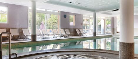 Zona de piscina con sillas de descanso, un jacuzzi y vistas al exterior.