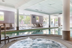 Ett poolområde med solstolar, ett bubbelbad och utsikt över omgivningarna.