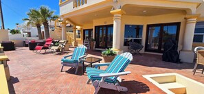 A covered patio with outdoor furniture, a pool, and a view of the surrounding buildings.