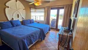 Habitación de hotel con dos camas, un gran adorno en la pared, ventilador de techo y vistas al exterior.