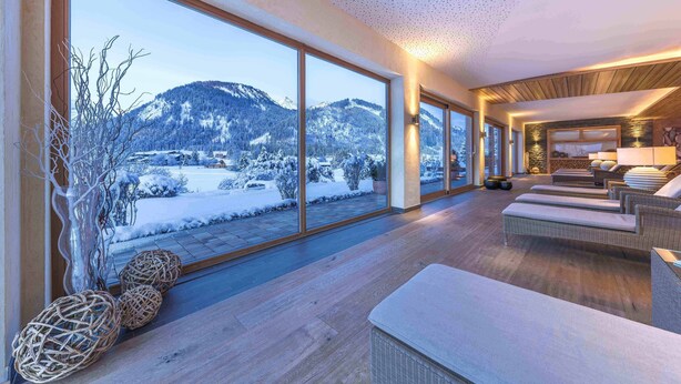 Un intérieur moderne avec de grandes fenêtres donnant sur un paysage montagneux enneigé.