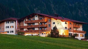 Un hôtel à plusieurs étages, doté de balcons, situé dans un cadre montagneux.