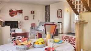 Zona de menjador amb taula preparada per esmorzar, incloent fruita, pa i begudes.