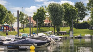 Ein Yachthafen mit vertäuten Booten, ein Spielplatz und ein Gebäude mit rotem Dach im Hintergrund.