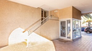 Ein Gebäude mit einer Treppe zu einem oberen Stockwerk, einem gläsernen Bereich mit Tisch und Stühlen sowie einem geparkten Auto davor.