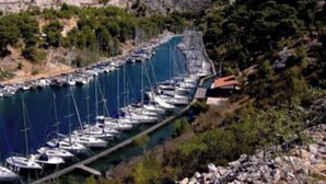 Ein Yachthafen mit zahlreichen Booten, die an einem schmalen Kanal liegen, umgeben von steilen Klippen und üppiger Vegetation.