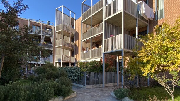 A multi-story residential building with balconies, a paved courtyard, and surrounding greenery. - Serendipity Apartment-Your home in Venice (Venezia)
