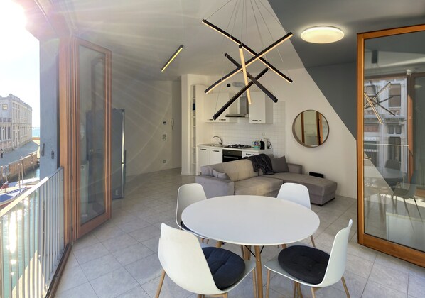 Une cuisine moderne avec des armoires blanches, un four encastré et un coin repas comprenant une table et des chaises blanches.