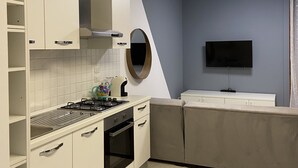 A compact kitchen with white cabinets, a gas stove, a microwave, and a built-in oven. - Serendipity Apartment-Your home in Venice (Venezia)