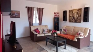 Un salon avec deux canapés, une table basse et un téléviseur posé sur un meuble.