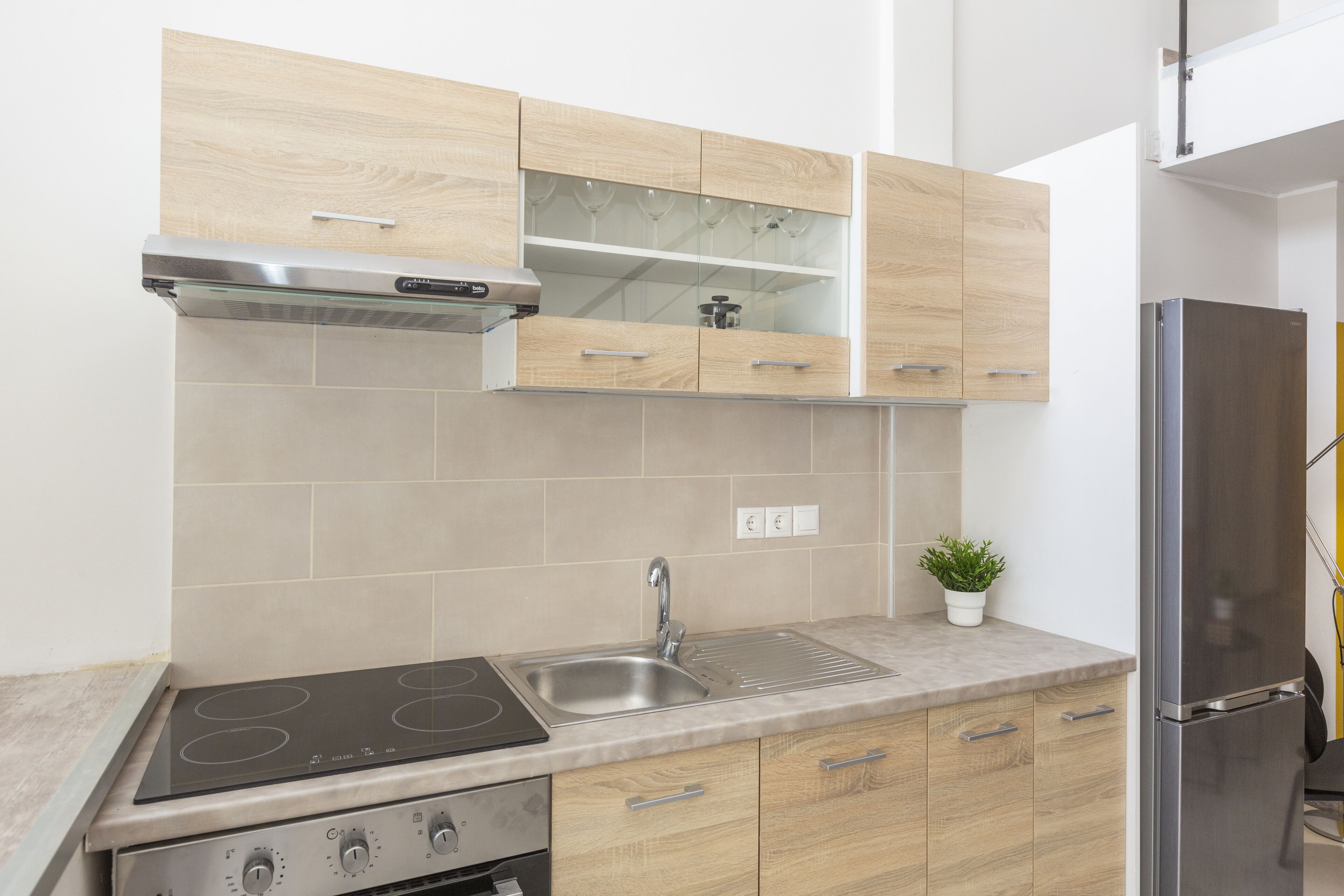 A modern kitchen with a stainless steel sink, a built-in oven, and wooden cabinets.