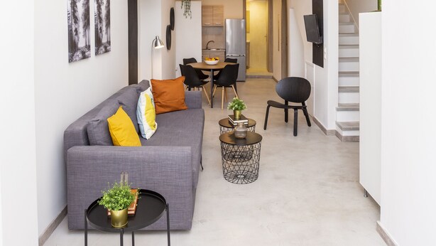 Un espace de vie moderne avec un canapé gris, une petite table ronde et un escalier.