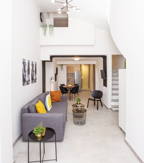 A modern living space with a gray sofa, a small round table, and a staircase.