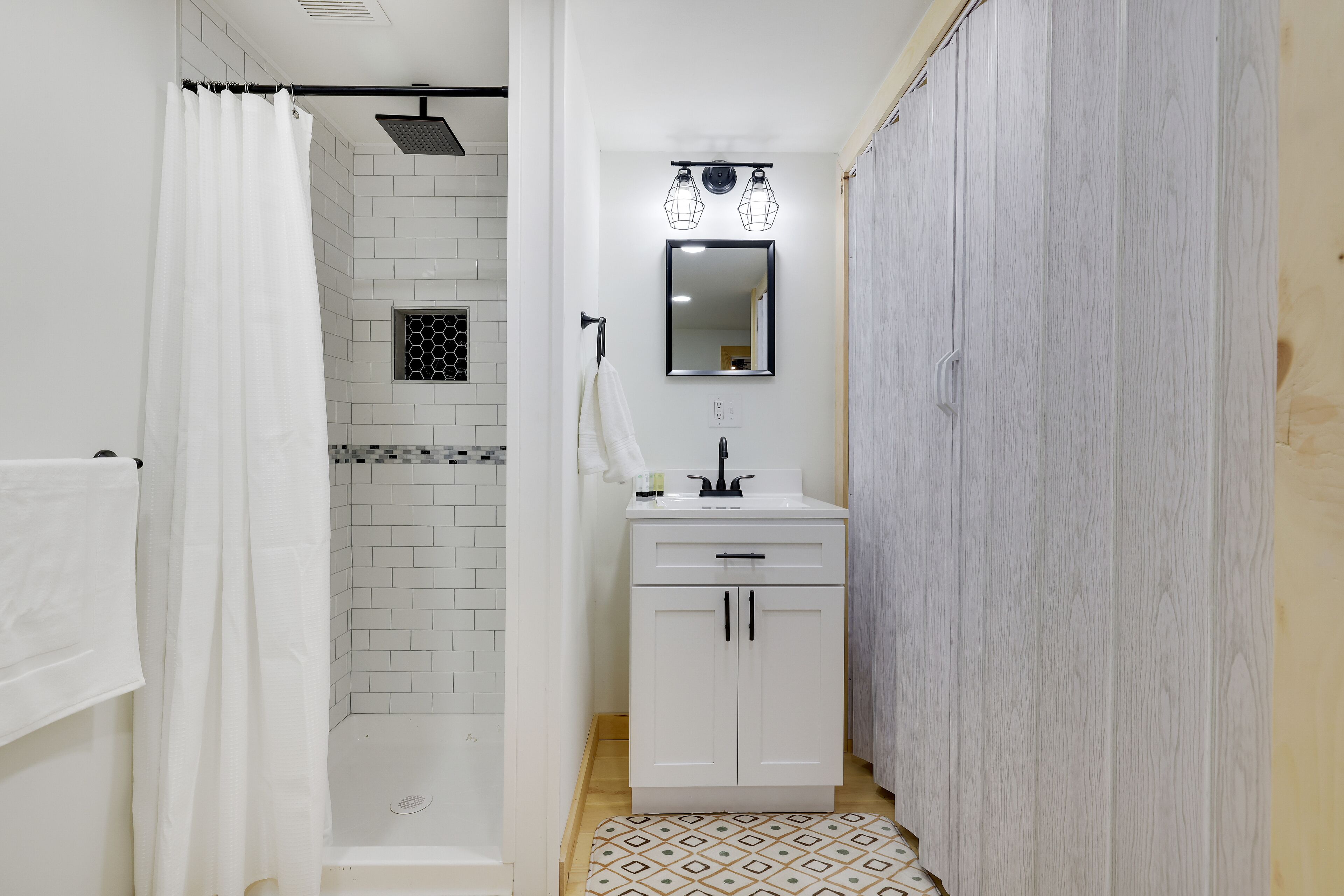 Ein Badezimmer mit Dusche, Waschbecken mit Spiegel und einem Schrank.