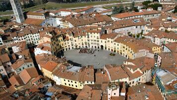 An aerial view of a historic town center with a central square, surrounding buildings, and a prominent tower.