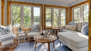 A cozy room with a sofa, chairs, a small table, and large windows.