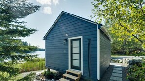 A small, dark blue cabin with a single door and a small porch.