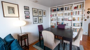 A dining area with a dark wooden table, four chairs, a bookshelf, and a framed artwork on the wall. - MONTMARTRE, PARIS VIEW, ATTRACTIONS, 30–60 days ahead? Ask Private offer VIE-VAp (Paris)