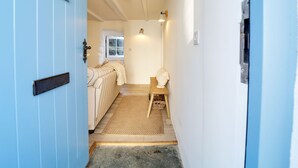 A narrow hallway leading to a room with a bed, a window, and a door. - This charming 18th Century cottage is centrally located in the heart of St Teath (St Teath)