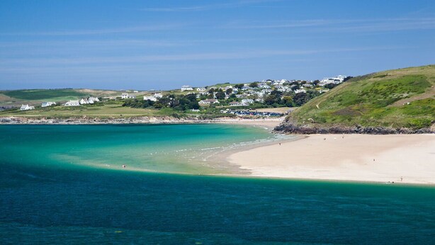 A coastal area with a sandy beach, clear turquoise waters, and a hillside with houses. - This charming 18th Century cottage is centrally located in the heart of St Teath (St Teath)
