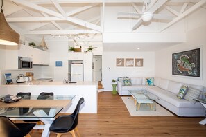 Un espace de vie moderne comprenant une cuisine, un coin repas et un salon avec un canapé et une table basse.