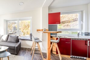 Une cuisine moderne avec des meubles de rangement rouges, une table en bois et une fenêtre donnant sur un jardin.