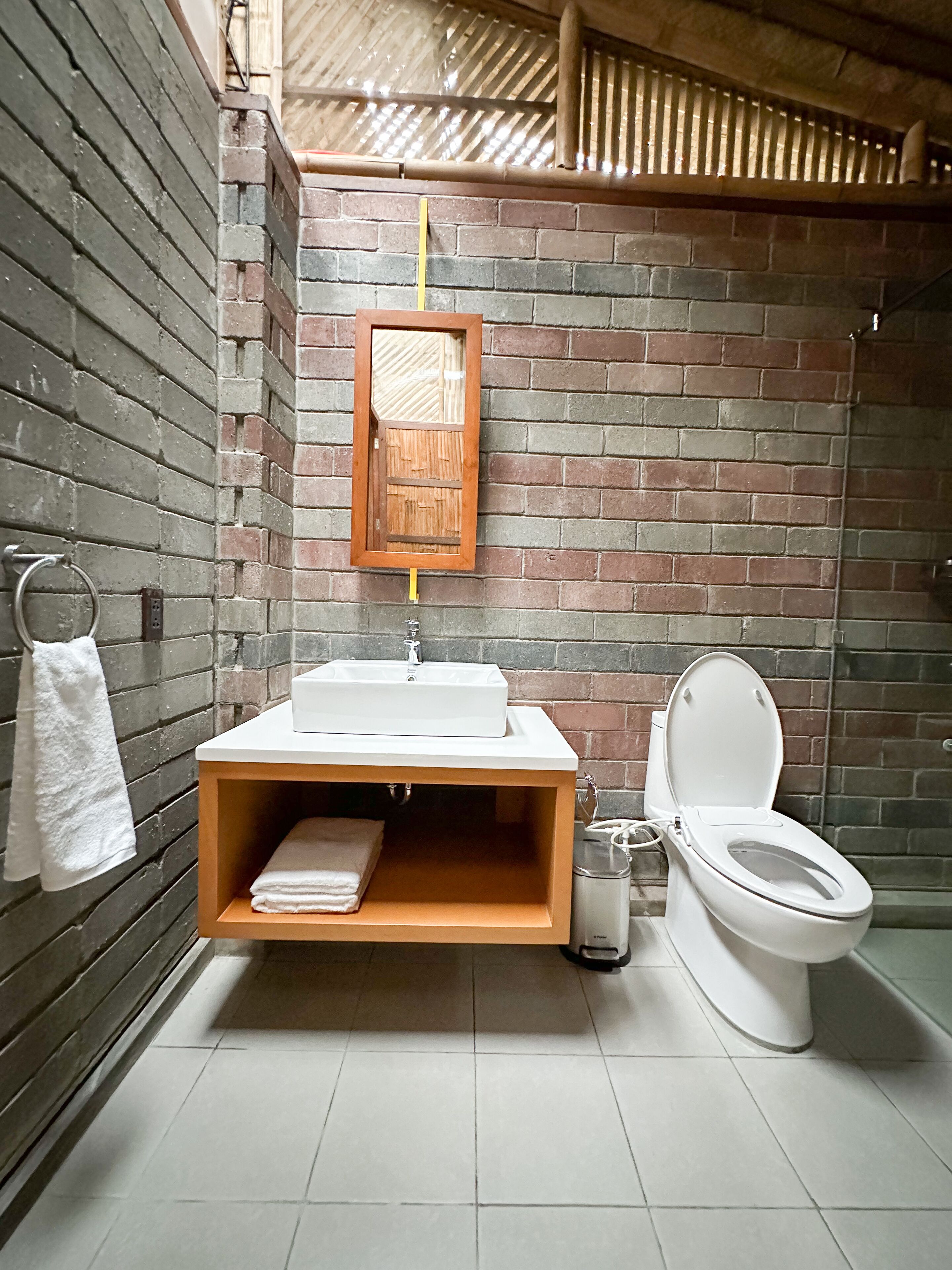 A bathroom with a wooden vanity, a white sink, and a toilet.