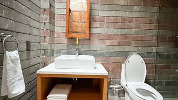 A bathroom with a wooden vanity, a white sink, and a toilet.