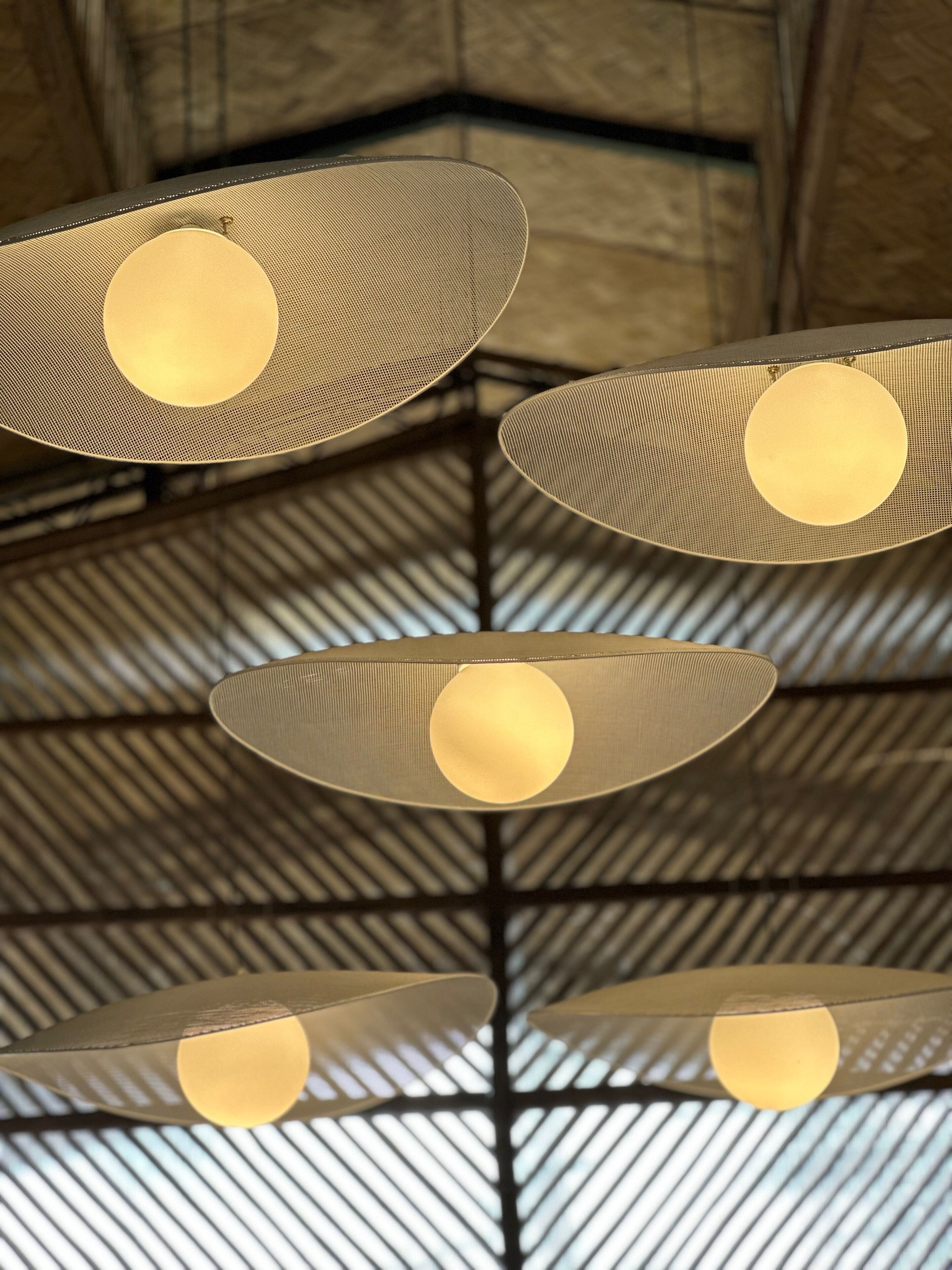 A ceiling with a geometric pattern and hanging lamps with circular shades.